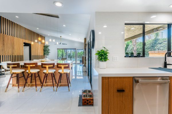 Open-concept kitchen and dining area with a wooden bar-height island and five wood bar stools under pendant lights.